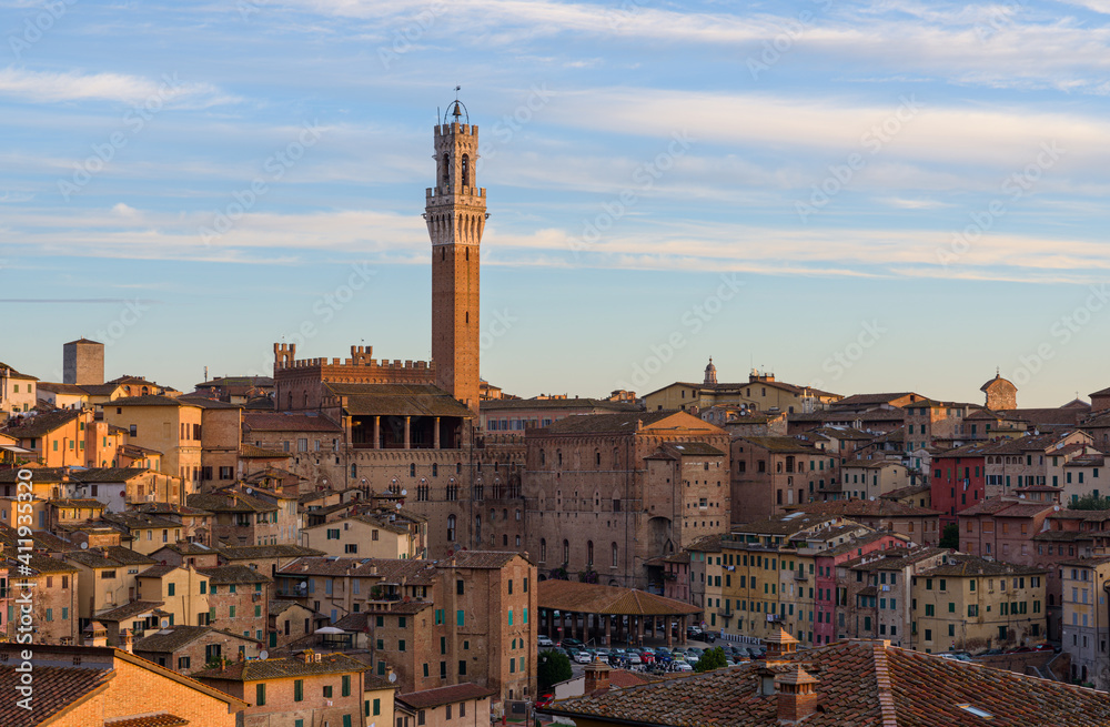Siena old town at sunrise, a medieval and Renaissance city in Tuscany, Italy, with Mangia tower, church, old houses and palaces on a green hill