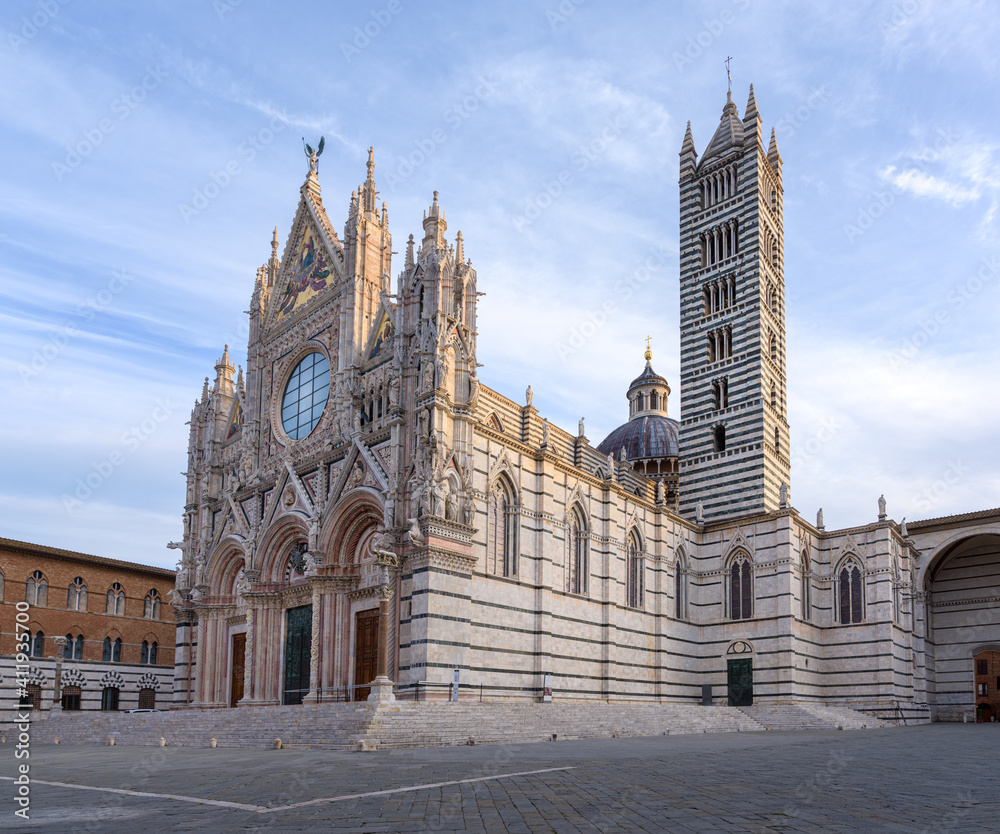Duomo di Siena at sunrise, a blakc and white marble church typical of medieval gothic architecture, in the famous Tuscany town of Siena, Italy