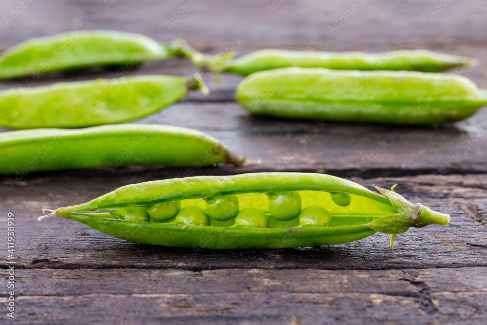 Green pea pods on a wooden background, harvest of peas