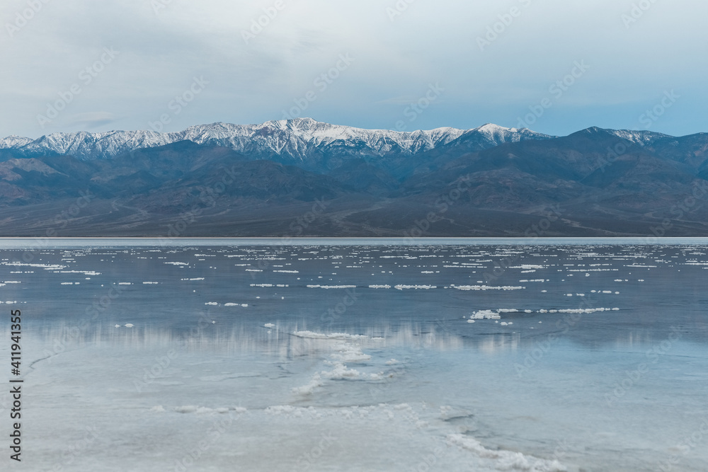 Blue hour with snow capped Telescope Peak reflecting in wet salt field of Death Valley