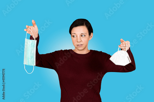 Junges Mädchen hält FFP2 Maske und Mund-Nasen-Schutz und schaut verwundert