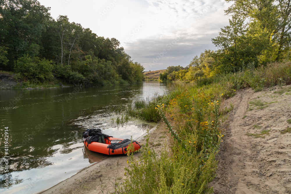 A kayak moored to the shore on the Khopyor River. The flow of the river stretching into the distance. Sandy shore.
