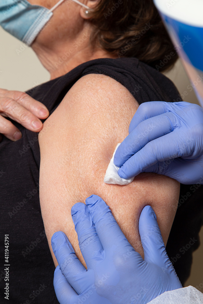 Obraz premium nurse uses alcohol swab on older woman's arm