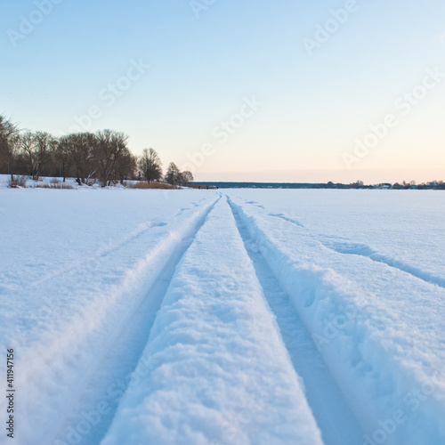 ski track in the snow. in the photo-a ski track on white snow, in a large snow-covered field, close-up, in the background the evening sky © fotofotofoto