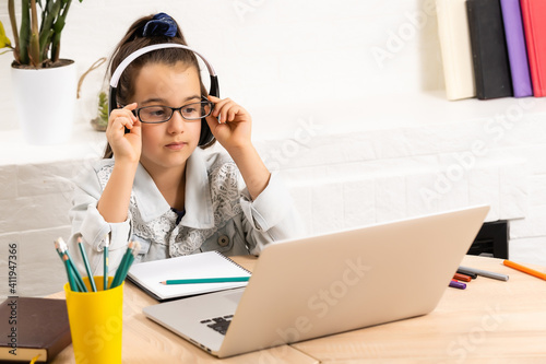 Child online. A little girl uses a laptop video chat to communicate learning while sitting at home.