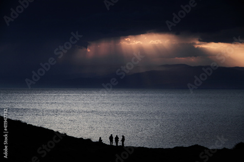 Four people backlit in an oceanfront sunset scene Fototapet