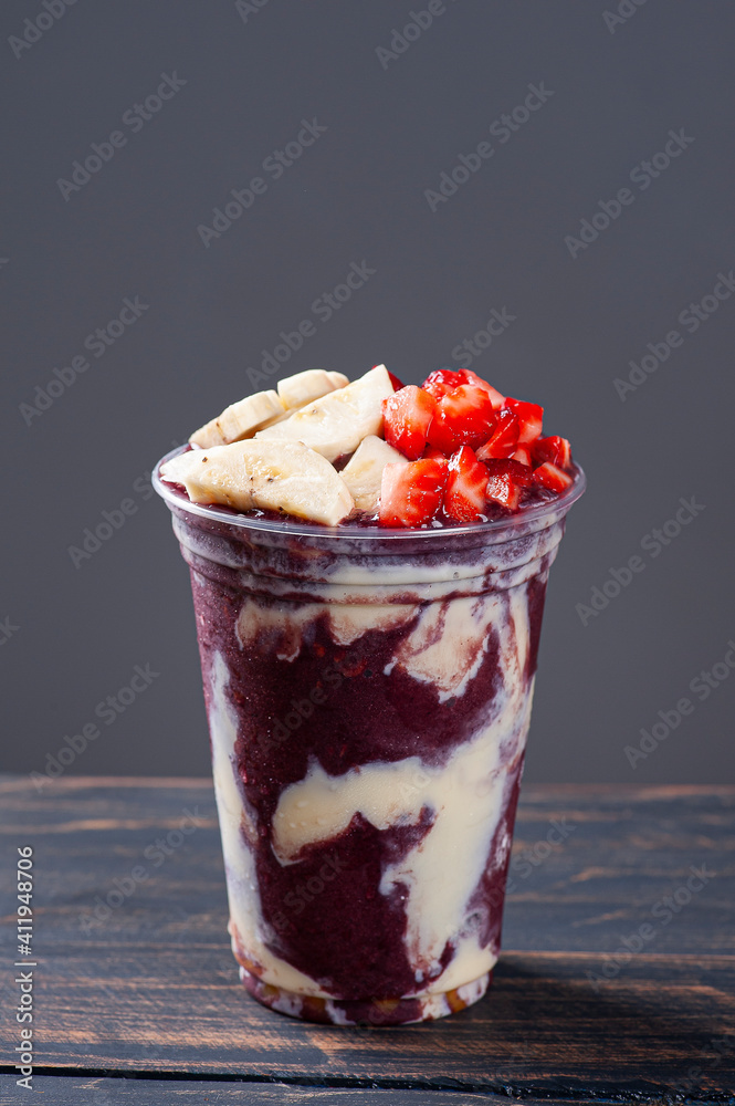 Brazilian frozen açaí in a plastic cup with condensed milk, banana and  strawberry. Fruit from the Amazon. Copy space Stock Photo | Adobe Stock