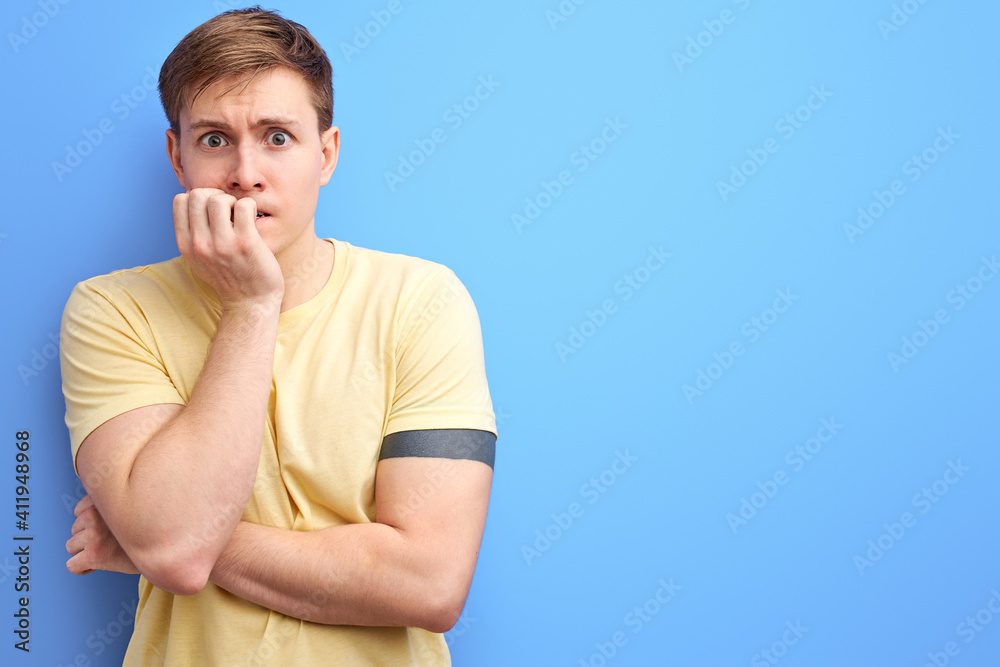 caucasian guy is looking stressed and nervous with hands on mouth biting nails. anxiety problem. isolated blue background caucasian guy is looking stressed and nervous with hands on mouth biting nails. anxiety problem. isolated blue background