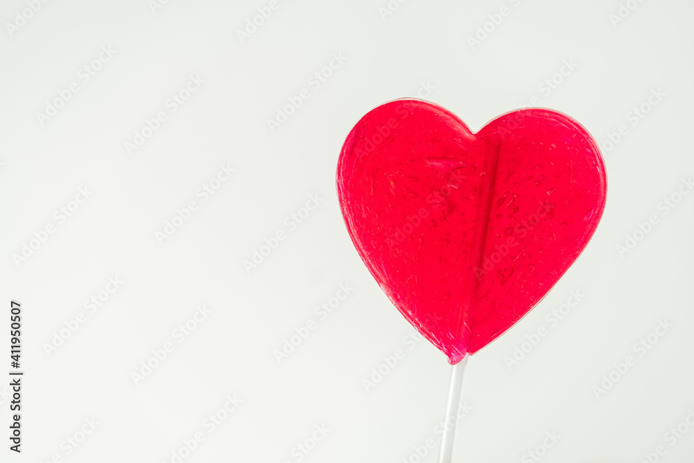 Close-up of red heart-shaped lollipop with white background.