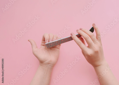 Manicure Top view photo with copy space Girl is filing her nails with nail file against pink background