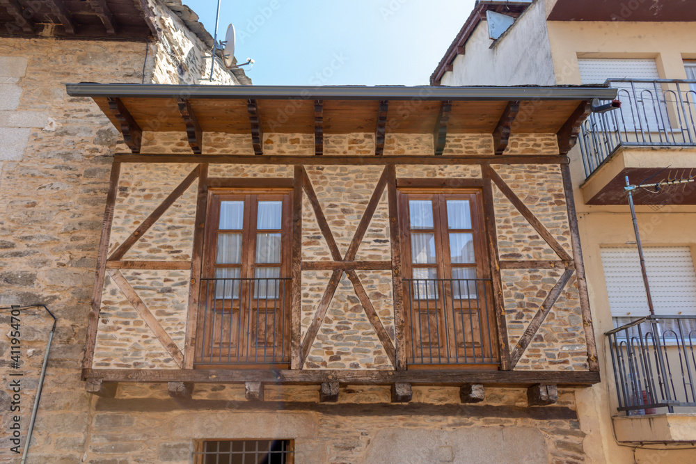 Puebla de Sanabria, Spain - September 6, 2020: Cobblestone street with picturesque stone residential buildings and flowered balconies in Puebla de Sanabría, Zamora province, Castilla y León. Puebla de Sanabria, Spain - September 6, 2020: Cobblestone street with picturesque stone residential buildings and flowered balconies in Puebla de Sanabría, Zamora province, Castilla y León.