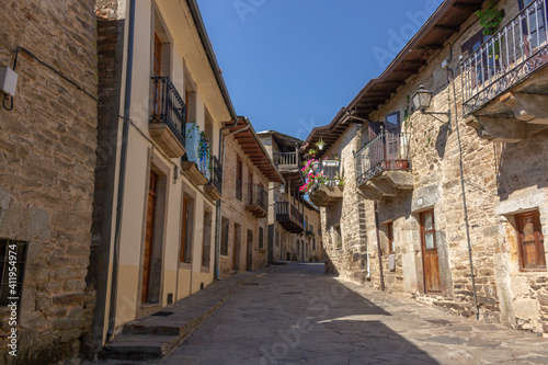 Puebla de Sanabria, Spain - September 6, 2020: Cobblestone street with picturesque stone residential buildings and flowered balconies in Puebla de Sanabría, Zamora province, Castilla y León.