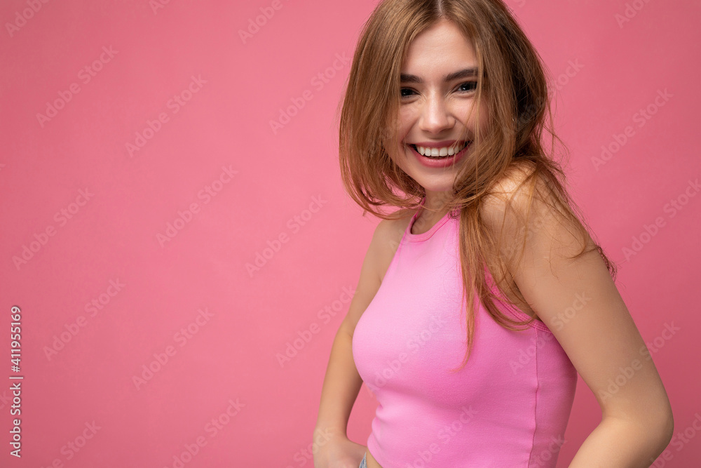 Photo shot of pretty joyful smiling young female person wearing casual trendy outfit standing isolated on colourful background with copy space looking at camera and having fun Photo shot of pretty joyful smiling young female person wearing casual trendy outfit standing isolated on colourful background with copy space looking at camera and having fun