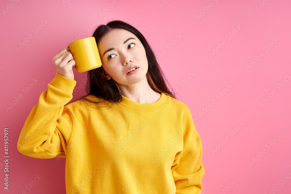 tired woman try to wake up in the morning, holding cup near head, want to sleep, looking at side, isolated over pink background tired woman try to wake up in the morning, holding cup near head, want to sleep, looking at side, isolated over pink background