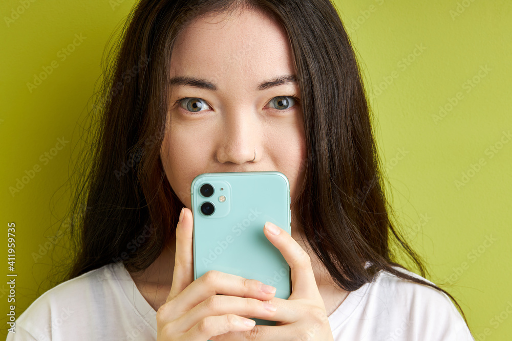 young woman hiding secret information, message in the smartphone isolated on green background, keep secret in the cell phone young woman hiding secret information, message in the smartphone isolated on green background, keep secret in the cell phone