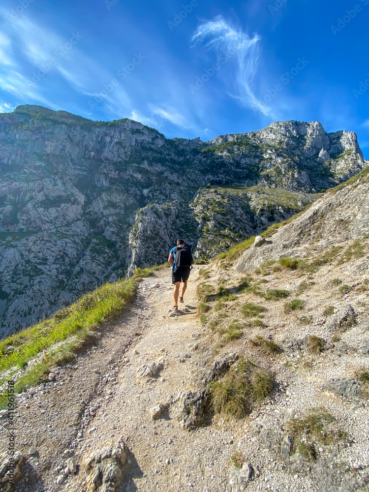 Hiker hike the Cares Route in the heart of Picos de Europa National Park, Cain-Poncebos, Spain. Narrow and impressive canyon between cliffs, caves and footpaths.