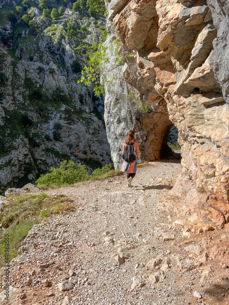 Cain, Spain - September 1, 2020: Female hiking trough the Cares Route in the heart of Picos de Europa National Park, Spain. Narrow and impressive canyon between cliffs, bridges and footpaths. Cain, Spain - September 1, 2020: Female hiking trough the Cares Route in the heart of Picos de Europa National Park, Spain. Narrow and impressive canyon between cliffs, bridges and footpaths.