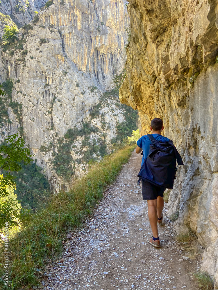 Hiker hike the Cares Route in the heart of Picos de Europa National Park, Cain-Poncebos, Spain. Narrow and impressive canyon between cliffs, caves and footpaths. Hiker hike the Cares Route in the heart of Picos de Europa National Park, Cain-Poncebos, Spain. Narrow and impressive canyon between cliffs, caves and footpaths.