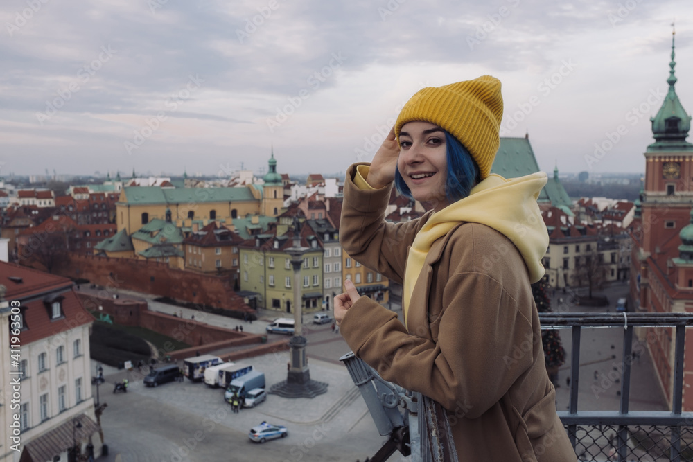 Happy young woman portrait with colored blue hair in coat in front of old town and Christmas tree