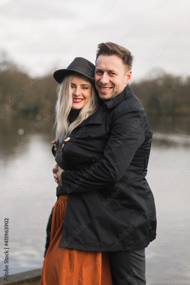 Gentleman covering his girlfriend with a jacket a cold autumn day on a pier Gentleman covering his girlfriend with a jacket a cold autumn day on a pier