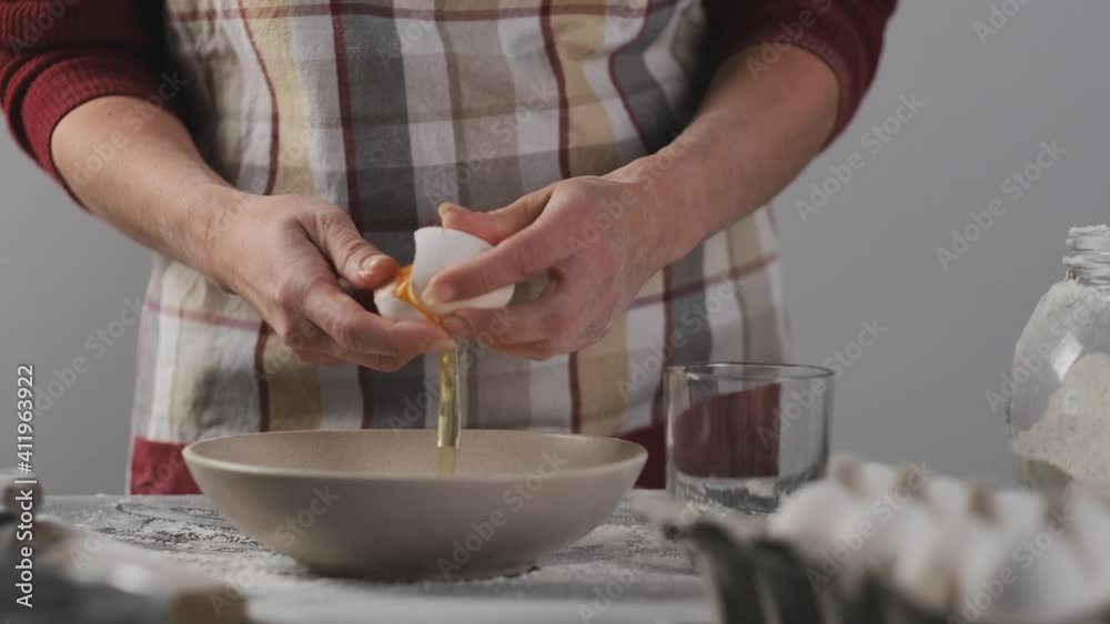 Woman separating egg for yolk and white during baking at home Woman separating egg for yolk and white during baking at home