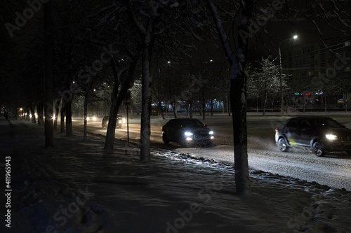 cars at night go along a snowy track