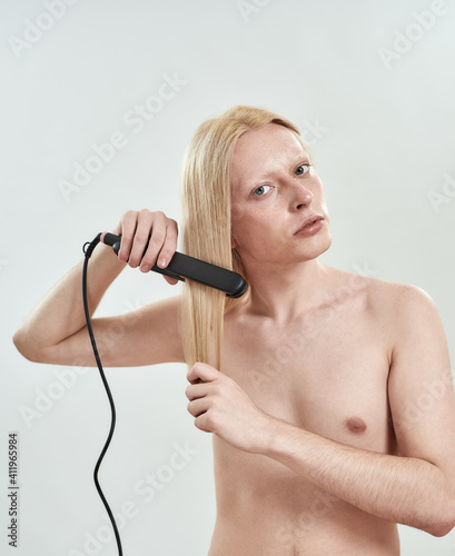 Young boy using tool for straightening long blond hair
