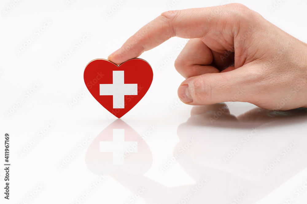 Love and respect Switzerland. A man's hand holds a heart in the shape of the Switzerland flag on a white glass surface. The concept of Swiss patriotism and pride. Love and respect Switzerland. A man's hand holds a heart in the shape of the Switzerland flag on a white glass surface. The concept of Swiss patriotism and pride.