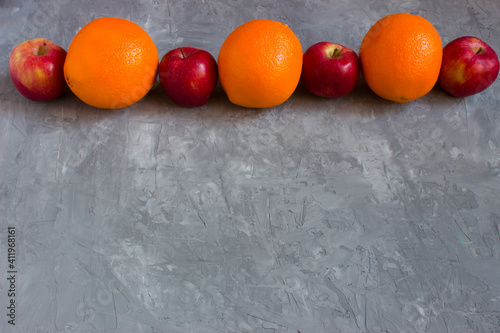 Healthy food. Oranges and apples on a grey concrete background with copyspace. © DK_2020