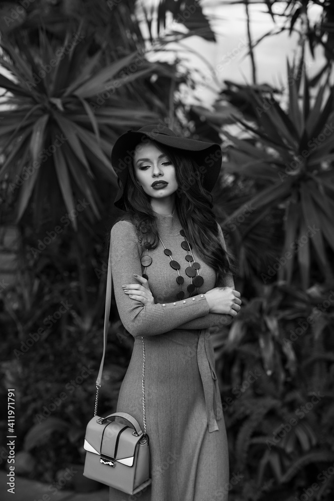 Fototapeta premium Waist-up portrait of young woman wearing knitted dress and wide-brimmed hat