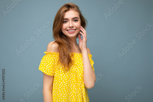 Photo of beautiful positive smiling adult woman wearing stylish clothes standing isolated on colorful background with copy space looking at camera