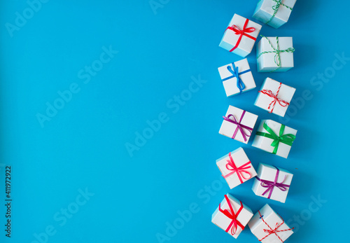 White boxes with colored ribbons lie on a blue background. Top view. Space for the text.