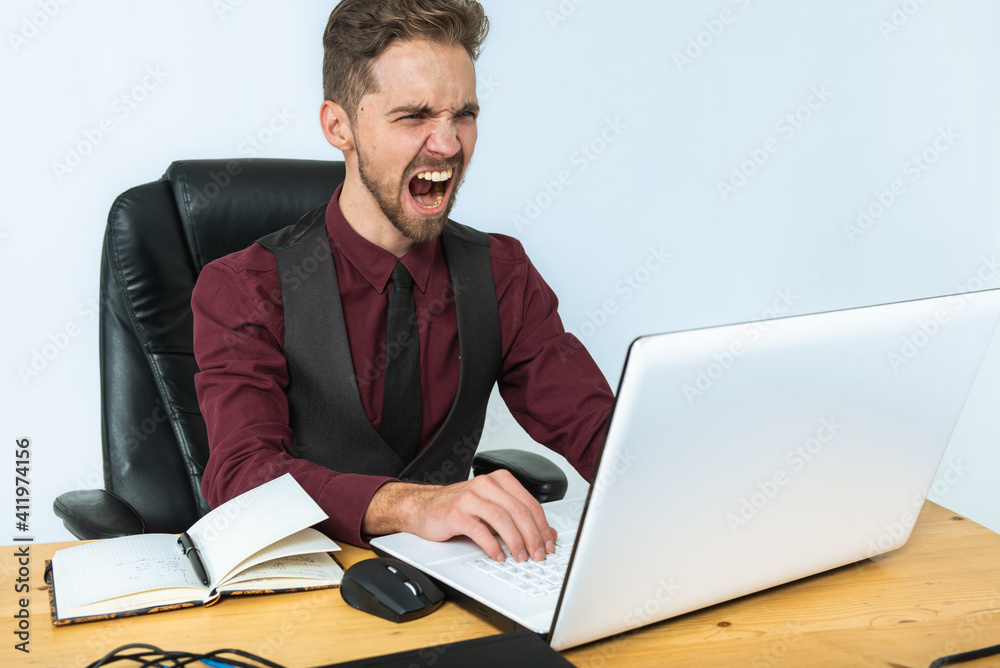 young handsome, focused man, businessman with beard, sitting working at desk near laptop at workplace bright office, writing e-mail, searching for information young handsome, focused man, businessman with beard, sitting working at desk near laptop at workplace bright office, writing e-mail, searching for information