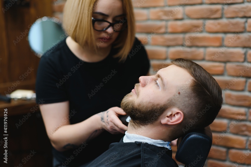 Fototapeta premium Client during beard shaving in barber shop