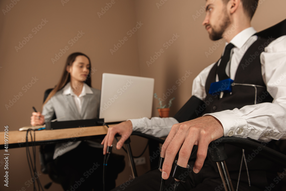 A woman's special agent tests a lie detector and a polygraph test on a young suspect. The questions of the expert accused in the interrogation room record the reactions. The concept of truth and revel A woman's special agent tests a lie detector and a polygraph test on a young suspect. The questions of the expert accused in the interrogation room record the reactions. The concept of truth and revel