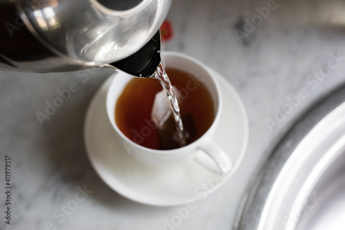 Pouring boiling water from jug into tea cup