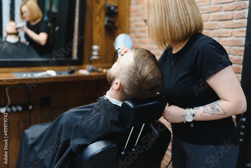 Barbershop or hairdresser concept. Woman hairdresser cuts beard with scissors. Man with long beard, mustache and stylish hair. Guy with modern hairstyle visiting hairdresser