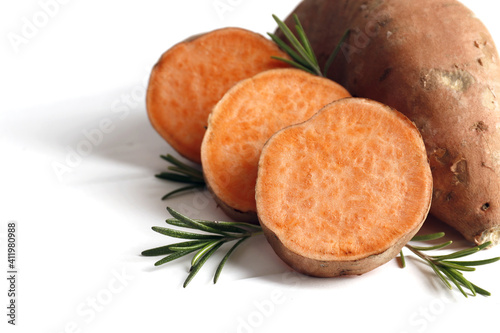 Sweet potatoes and rosemary spice on table against color background