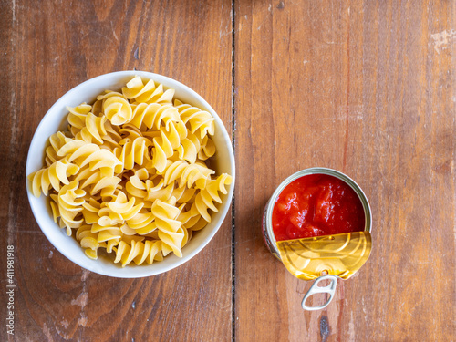 Top view of fusilli giganti on bowl with fried tomato in a can on wood table. Pasta recipe. High resolution