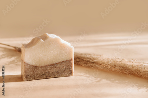 Handmade soap and pampas grass. Sunshade shadow on beige background. Zero waste, eco friendly cosmetics concept. Vintage color filter photo