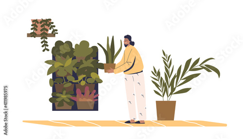 Woman creating vertical garden on wall at home. Female gardener caring for plants in pot