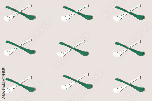 Pattern made of criss-crossed two hurly sticks – hurleys in green and white color with shamrock decoration.  Flat lay against beige background. photo