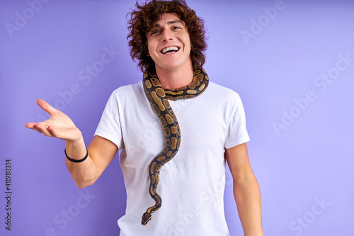 guy stand with snake on neck, he is brave, has no phobia, speaking and smiling . isolated purple background