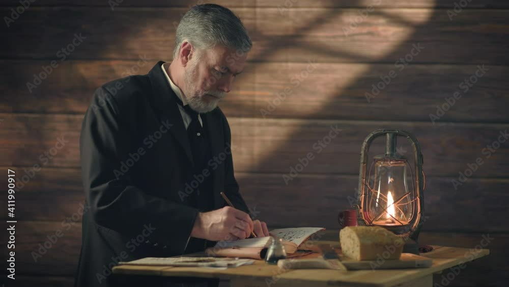 Overhead window light and an oil lantern illuminates this early 19th century scene of a gentleman standing next to a rustic table writing in his journal with a dip pen.