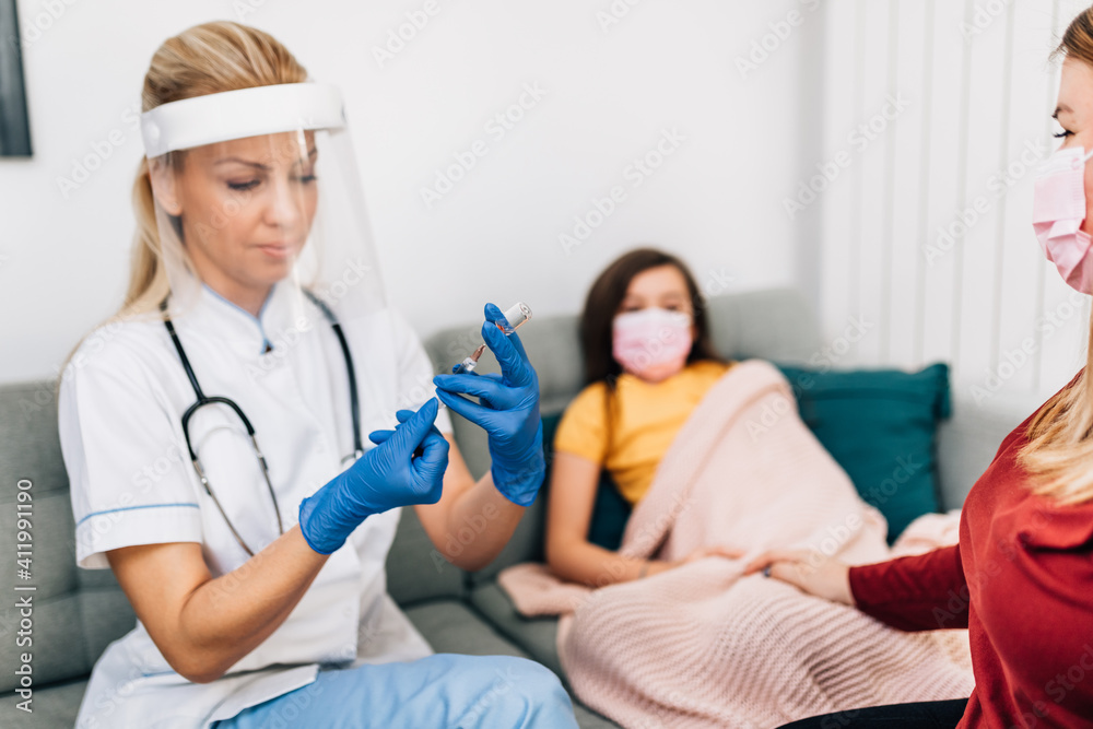 Female doctor vaccinating mother and daughter at their home. Coronavirus, Covid-19 concept. Female doctor vaccinating mother and daughter at their home. Coronavirus, Covid-19 concept.
