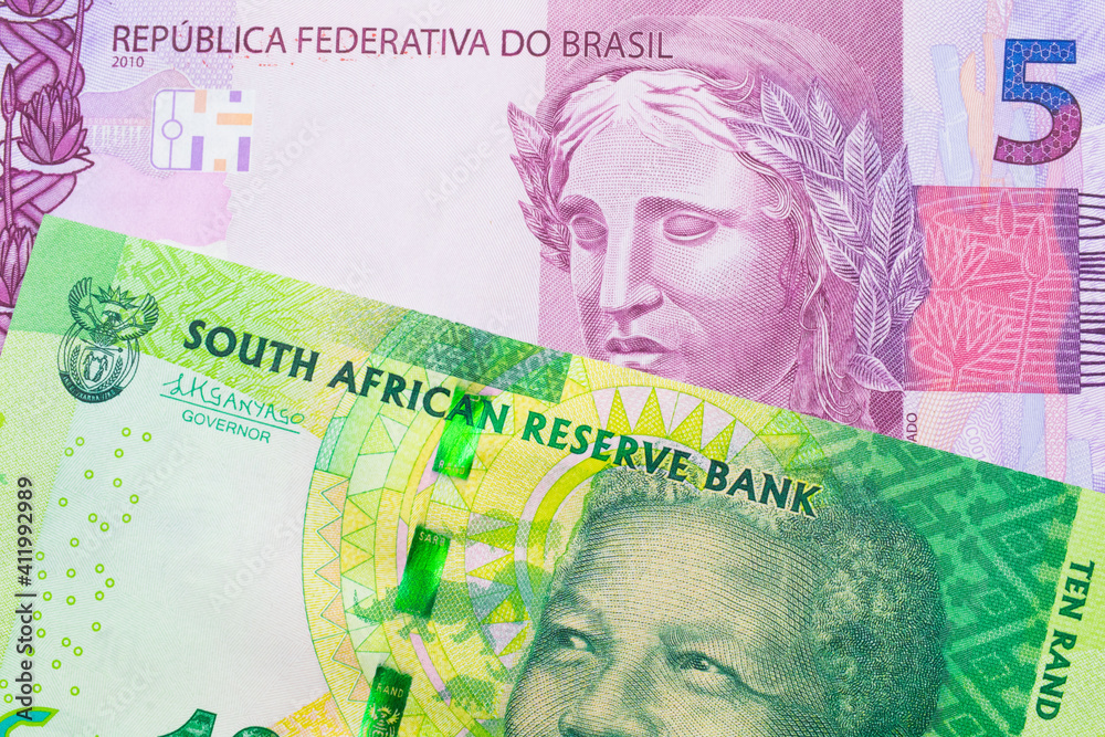 A macro image of a shiny, green 10 rand bill from South Africa paired up with a pink and purple five real bank note from Brazil.  Shot close up in macro.