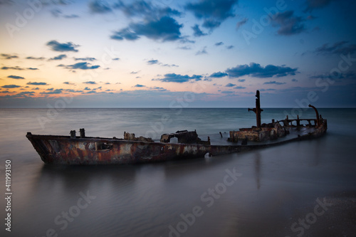 sunken boat stuck at shore at sunset time