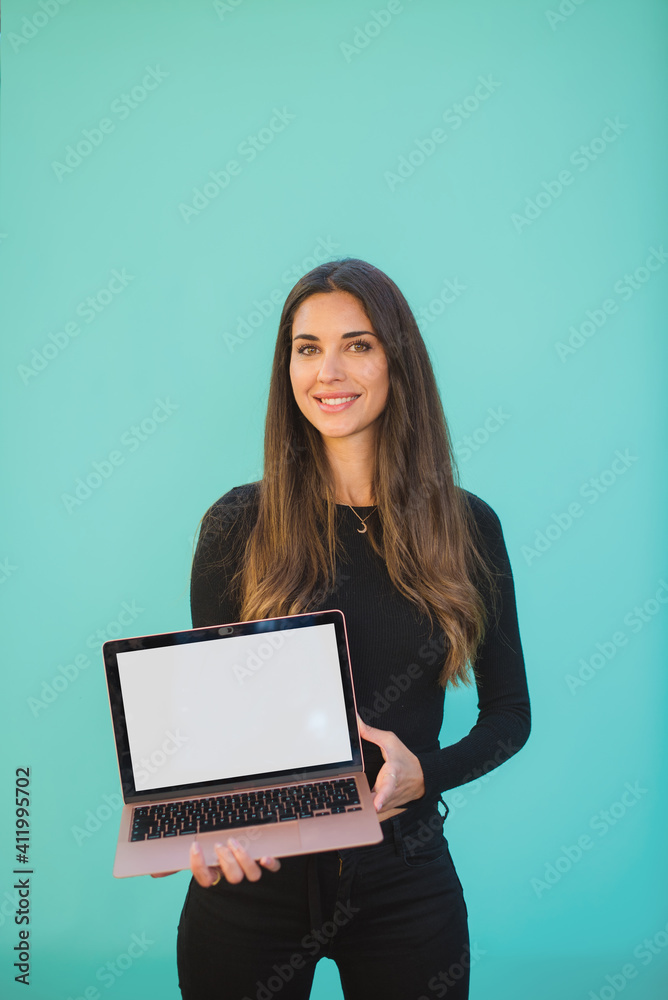 Happy caucasian woman holding laptop with white screen in her hand on a green aztec background. Focus on face Happy caucasian woman holding laptop with white screen in her hand on a green aztec background. Focus on face