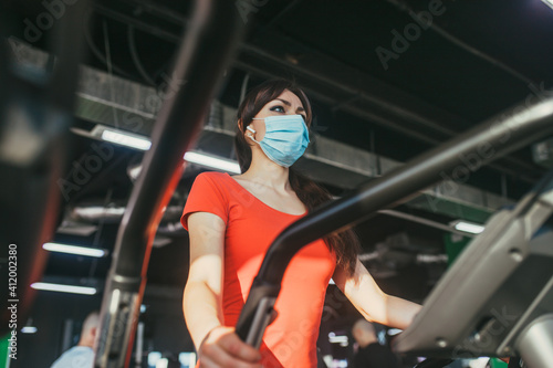 An active woman in a protective medical mask training in gym, during COVID-19 epidemic. Sport and quarantine.