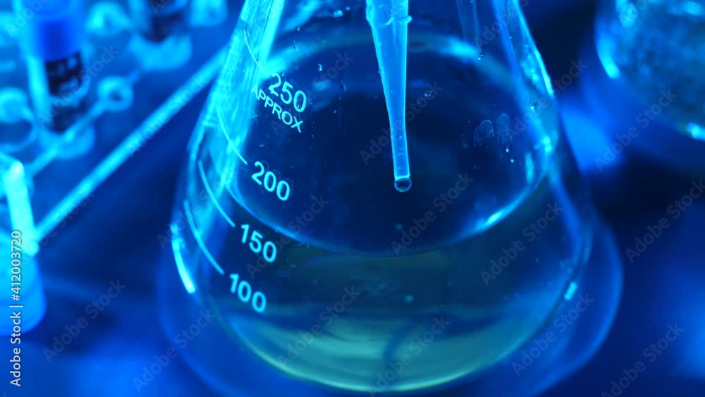 A dripper is dripping a liquid inside of a test tube in a laboratory A dripper is dripping a liquid inside of a test tube in a laboratory